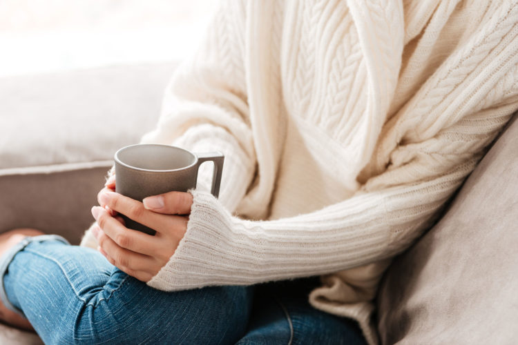 woman sitting on sofa with coffee cup