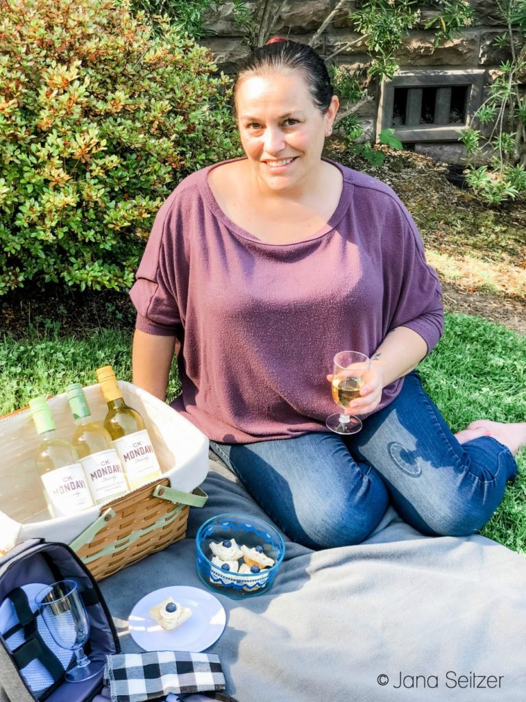 person with wine bottles and tarts in a picnic