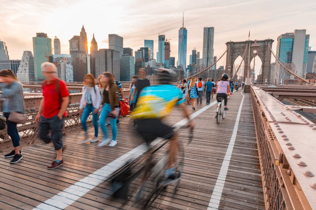 Tourists in New York on Brooklyn bridge with Manhattan skyscrapers on background
