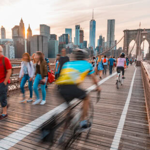 Tourists in New York on Brooklyn bridge with Manhattan skyscrapers on background